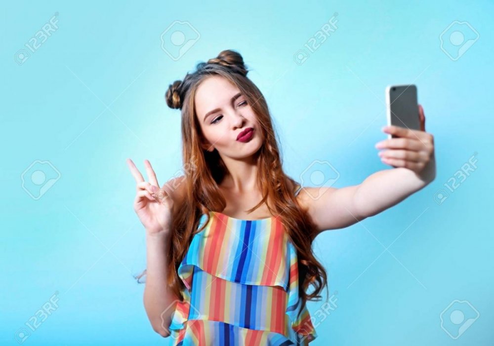 96788329-beautiful-teenager-girl-taking-selfie-on-blue-wall-background.jpg